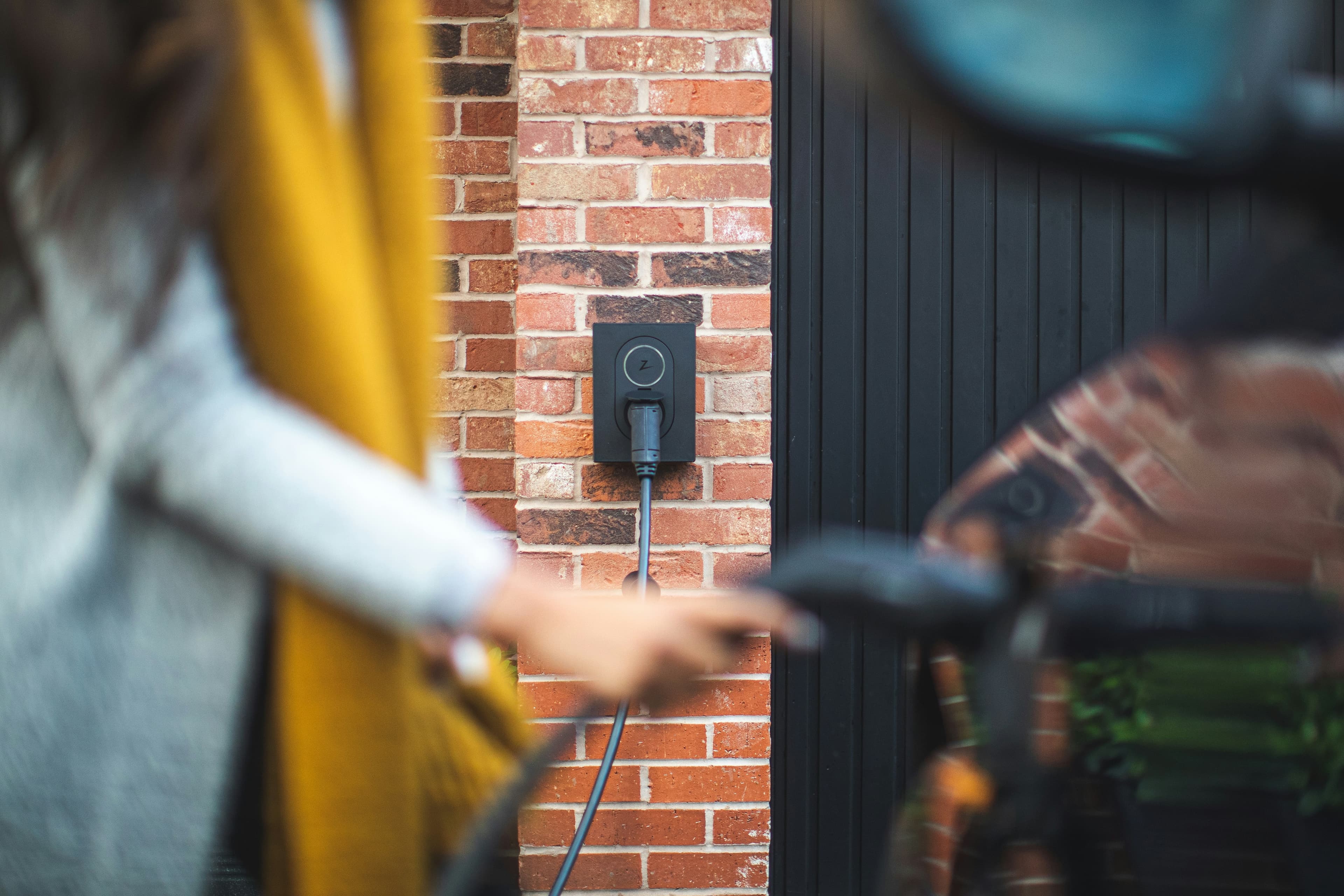 Driver approaching a private EV charger mounted outside a home